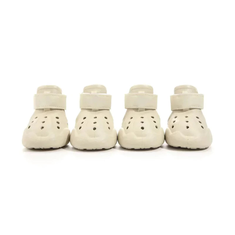 Four white dog shoes with straps on a white background